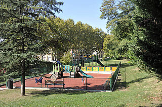 Une aire de jeux pour enfants composée de plusieurs éléments et entourée d'herbes.